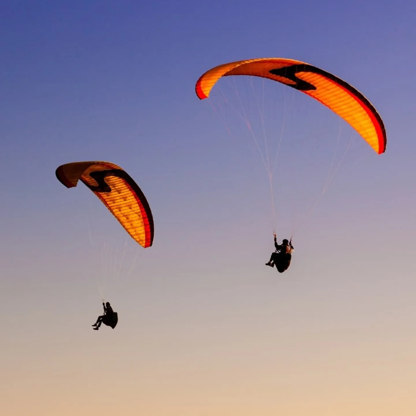 A paraglider catching the last light above the hills
